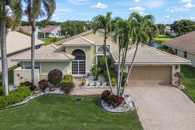 mediterranean / spanish-style home featuring a water view, a garage, and a front yard