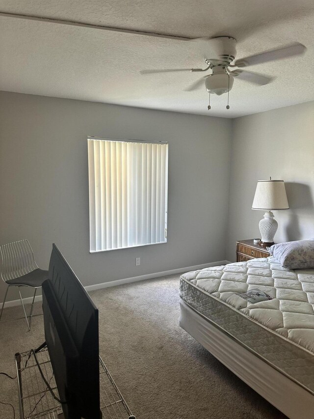 bedroom featuring ceiling fan, carpet, and a textured ceiling