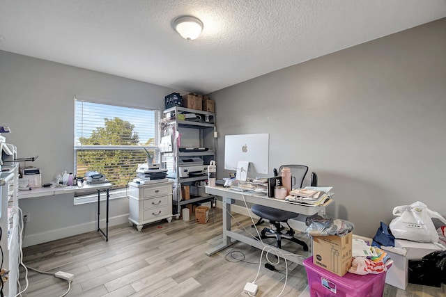 office space featuring light wood-type flooring and a textured ceiling