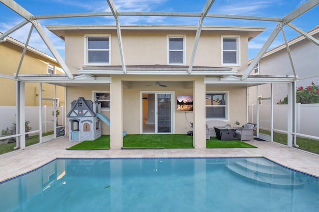 back of house featuring ceiling fan, a patio area, a fenced in pool, and glass enclosure