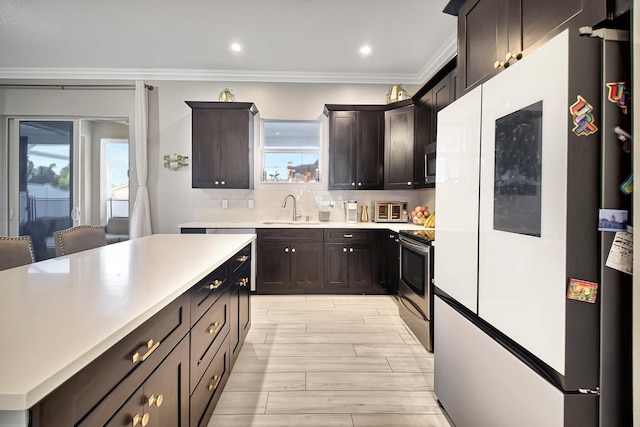 kitchen featuring dark brown cabinetry, sink, backsplash, appliances with stainless steel finishes, and ornamental molding