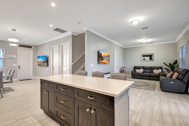 kitchen featuring pendant lighting, light wood-type flooring, a center island, and crown molding