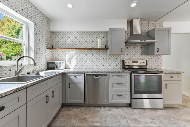 kitchen with stainless steel appliances, gray cabinets, wall chimney exhaust hood, and sink