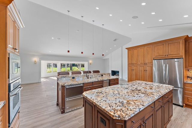 kitchen featuring pendant lighting, vaulted ceiling, built in appliances, light stone countertops, and a kitchen island