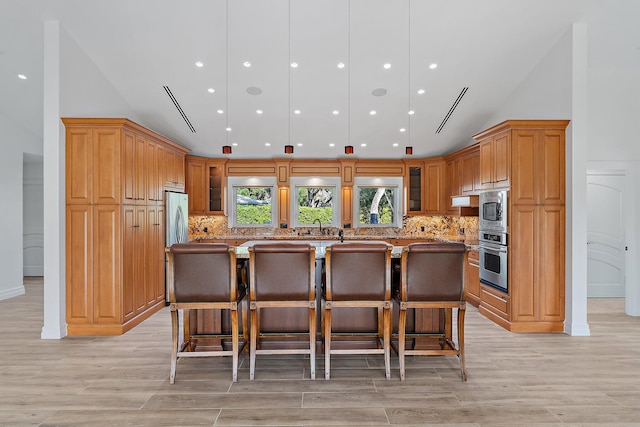 kitchen featuring light wood-type flooring, tasteful backsplash, a breakfast bar, stainless steel appliances, and a kitchen island