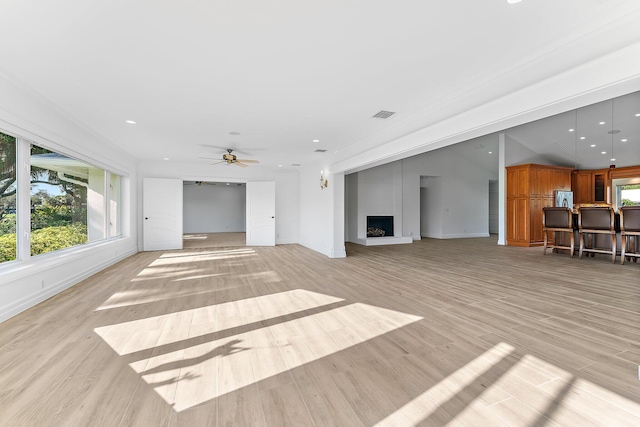 unfurnished living room featuring ceiling fan, a large fireplace, and light hardwood / wood-style flooring