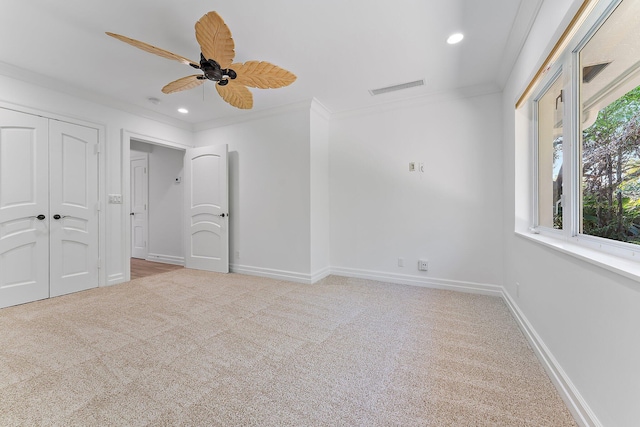 unfurnished bedroom featuring crown molding, ceiling fan, a closet, and light colored carpet