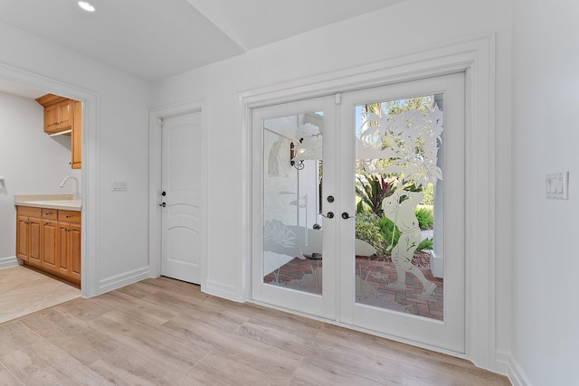 doorway to outside with sink, french doors, and light hardwood / wood-style flooring