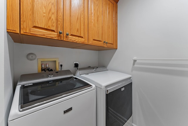 laundry area with washer and clothes dryer and cabinets