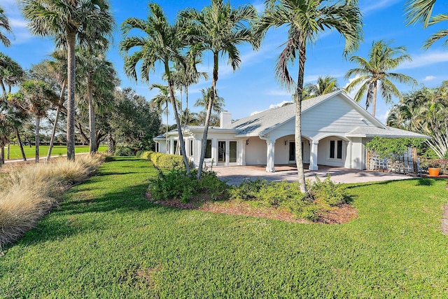 back of property with french doors, a patio, and a lawn