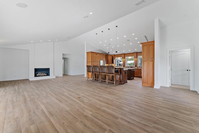 unfurnished living room featuring a large fireplace, high vaulted ceiling, and light hardwood / wood-style flooring