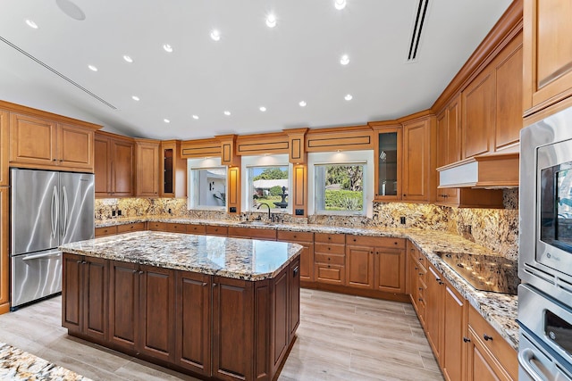 kitchen with appliances with stainless steel finishes, light wood-type flooring, a kitchen island, and sink