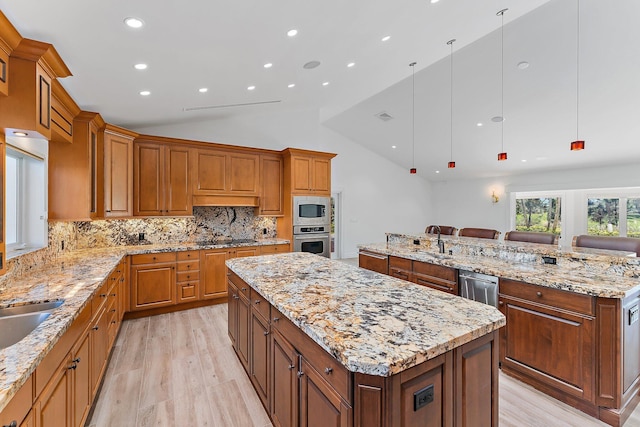 kitchen featuring pendant lighting, lofted ceiling, appliances with stainless steel finishes, tasteful backsplash, and a large island