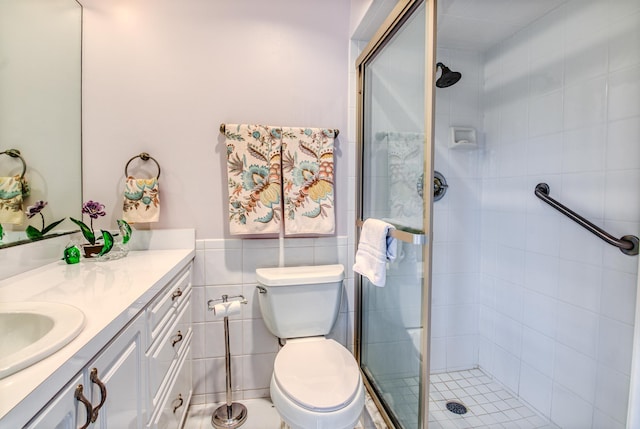 bathroom with vanity, toilet, a shower with door, and tile walls