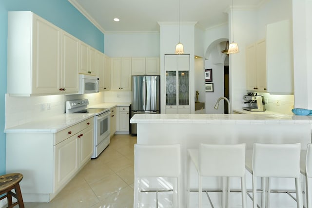 kitchen with backsplash, a kitchen bar, white appliances, and hanging light fixtures