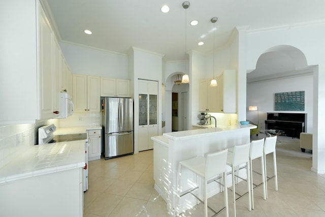 kitchen with white cabinetry, backsplash, kitchen peninsula, pendant lighting, and white appliances