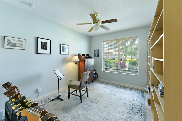 living area with a textured ceiling and ceiling fan