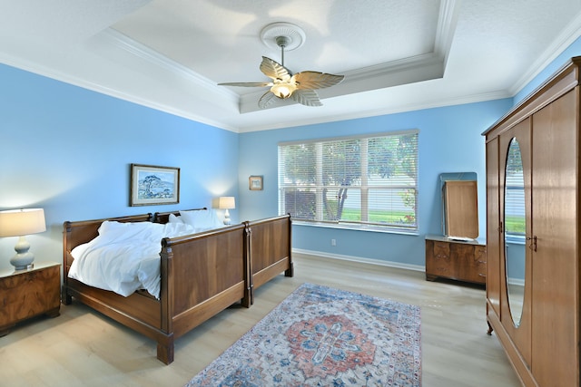 bedroom featuring a raised ceiling, ceiling fan, crown molding, and light hardwood / wood-style flooring