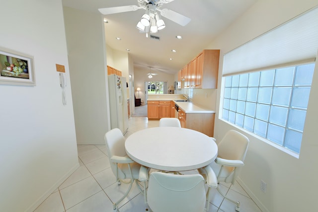 dining space with ceiling fan, sink, light tile patterned floors, and lofted ceiling