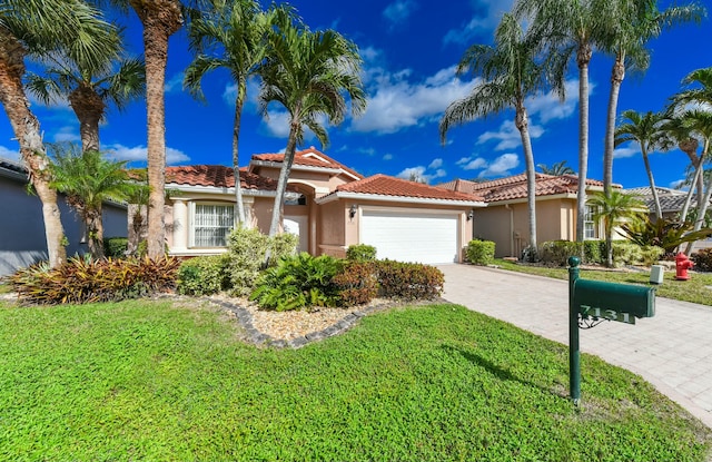 mediterranean / spanish house with a garage and a front lawn