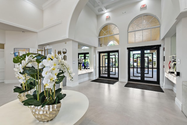 entryway with french doors, a high ceiling, and ornamental molding