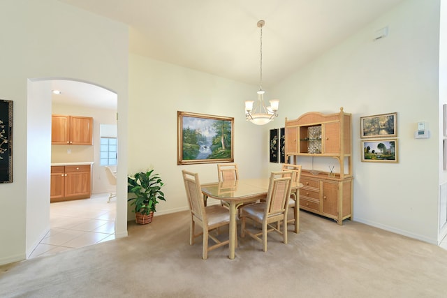 carpeted dining room with high vaulted ceiling and an inviting chandelier