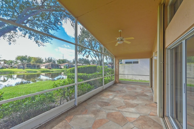 unfurnished sunroom with lofted ceiling, ceiling fan, and a water view