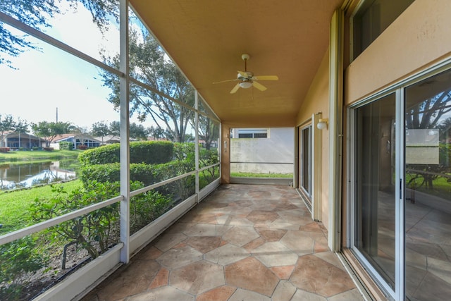 unfurnished sunroom featuring lofted ceiling, ceiling fan, and a water view