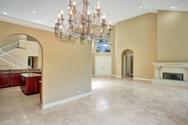 dining space featuring a high ceiling, sink, ornamental molding, a premium fireplace, and a chandelier