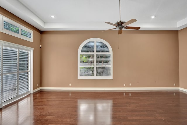 spare room featuring dark hardwood / wood-style floors, ceiling fan, and a tray ceiling