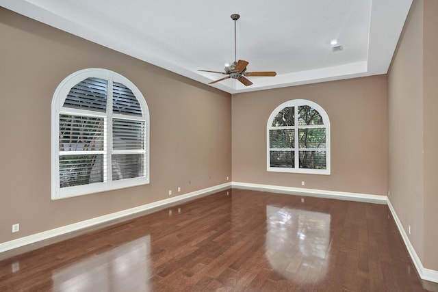 spare room with hardwood / wood-style floors, a raised ceiling, and ceiling fan