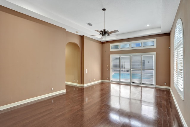 spare room featuring ceiling fan, dark hardwood / wood-style floors, and a raised ceiling