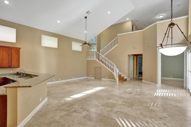 unfurnished living room with a towering ceiling, ceiling fan, and sink