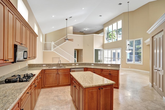 kitchen with ceiling fan, sink, a high ceiling, gas stovetop, and pendant lighting