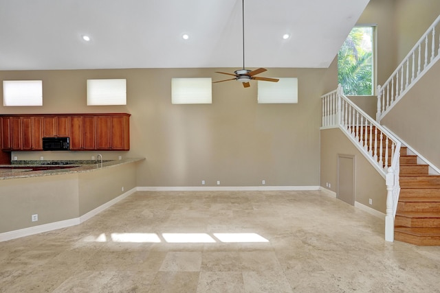 unfurnished living room featuring ceiling fan, sink, and a high ceiling