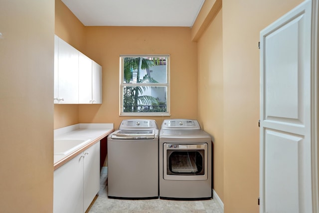 clothes washing area featuring washing machine and clothes dryer, sink, and cabinets