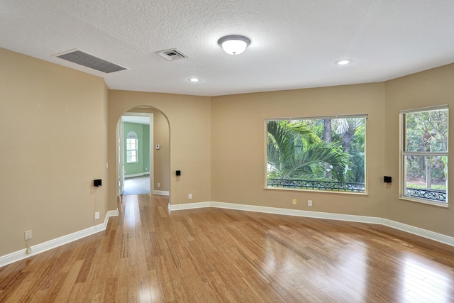 spare room with light hardwood / wood-style floors and a textured ceiling