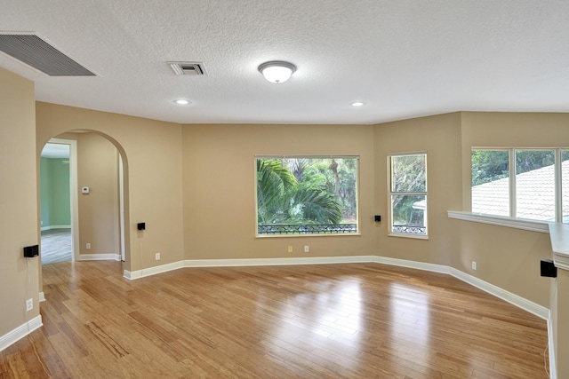 spare room featuring a textured ceiling and light hardwood / wood-style floors