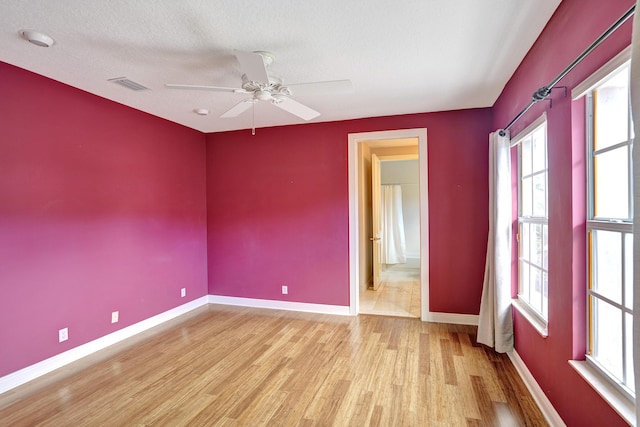 empty room with ceiling fan, light hardwood / wood-style flooring, and a textured ceiling