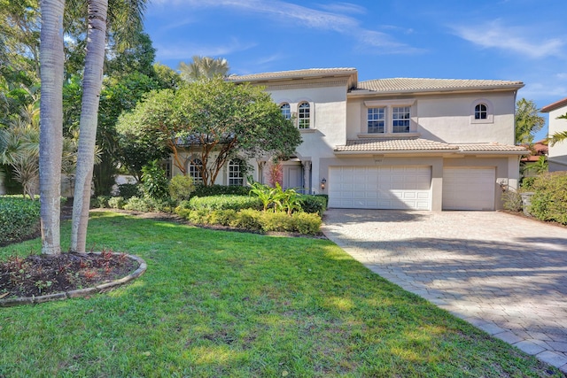 mediterranean / spanish-style home with a garage and a front lawn