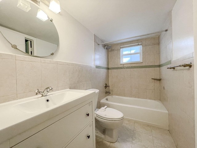 full bathroom featuring vanity, tile patterned floors, tiled shower / bath, toilet, and tile walls