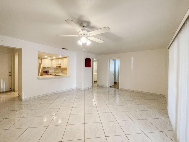 unfurnished living room featuring ceiling fan, sink, and light tile patterned flooring