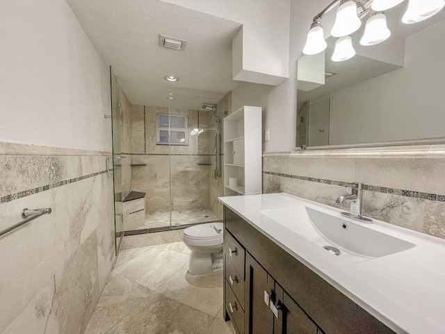 bathroom with vanity, a shower with door, toilet, a textured ceiling, and tile walls