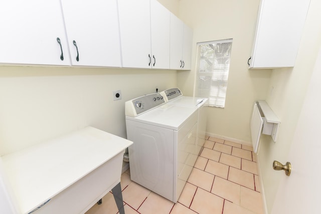 clothes washing area with washer and clothes dryer, light tile patterned floors, and cabinets