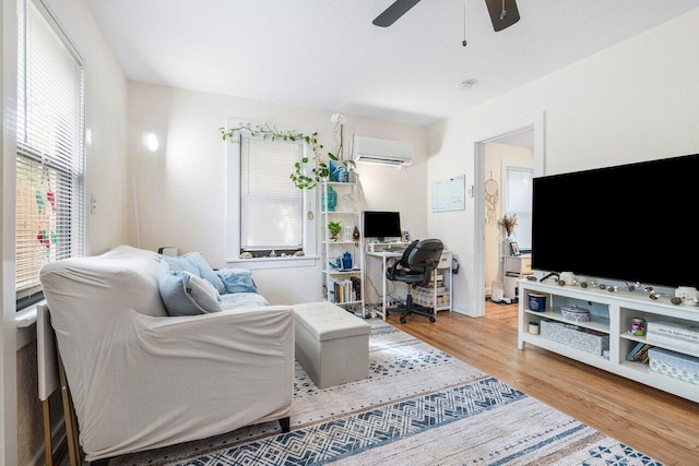 living room featuring light hardwood / wood-style floors, a wall mounted AC, and ceiling fan