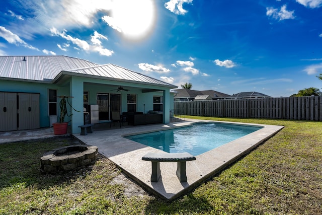 view of swimming pool with ceiling fan, a yard, a patio, and an outdoor living space with a fire pit