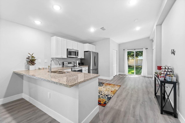 kitchen featuring sink, appliances with stainless steel finishes, white cabinetry, light stone counters, and kitchen peninsula