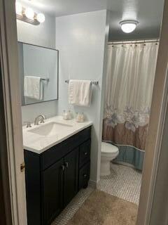 bathroom with a shower with curtain, tile patterned flooring, vanity, and toilet