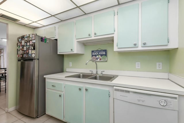 kitchen with light tile patterned floors, white dishwasher, stainless steel refrigerator, and sink