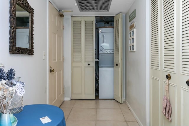 hallway featuring light tile patterned floors and stacked washer and dryer